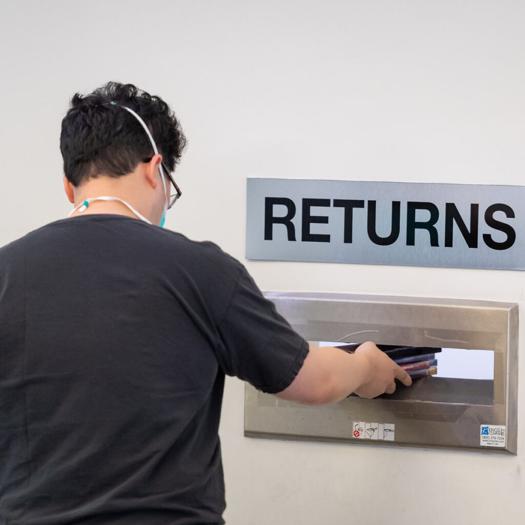 person returning free books in a library drop box