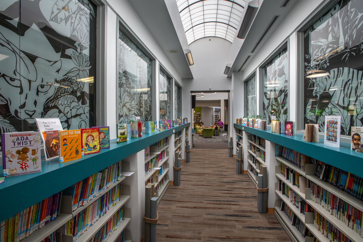 a hallway with bookshelves jungle window decals and nautical decor.