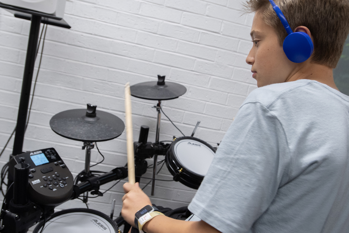 Teenager playing electronic drum set.