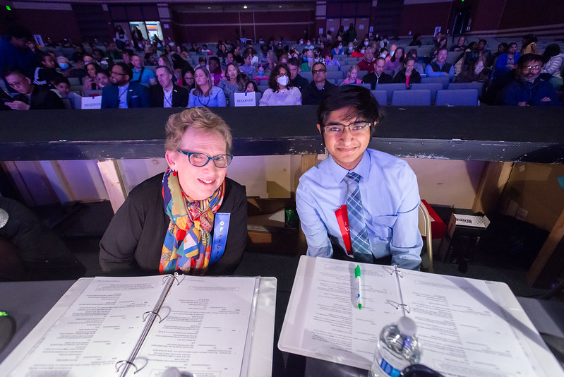 Previous spelling bee winner and friends chair sitting at judges table.