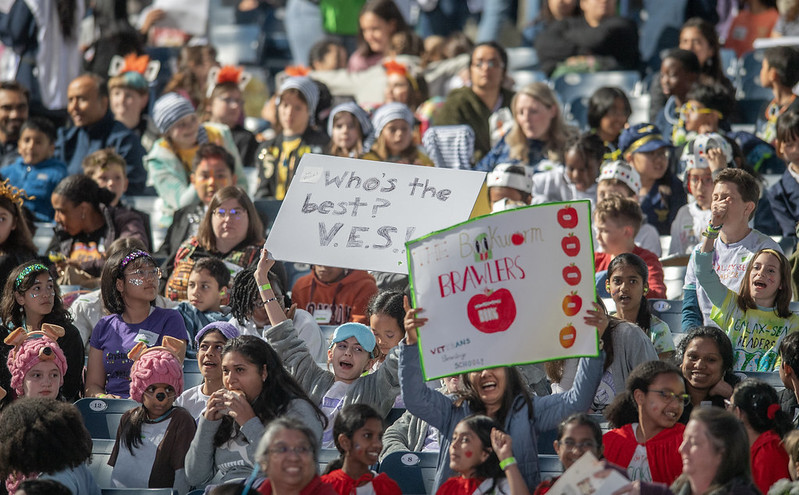 5th Grade students holding team posters in the air.