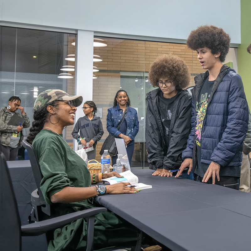 Two teenage boys talking to an author at a book signing.