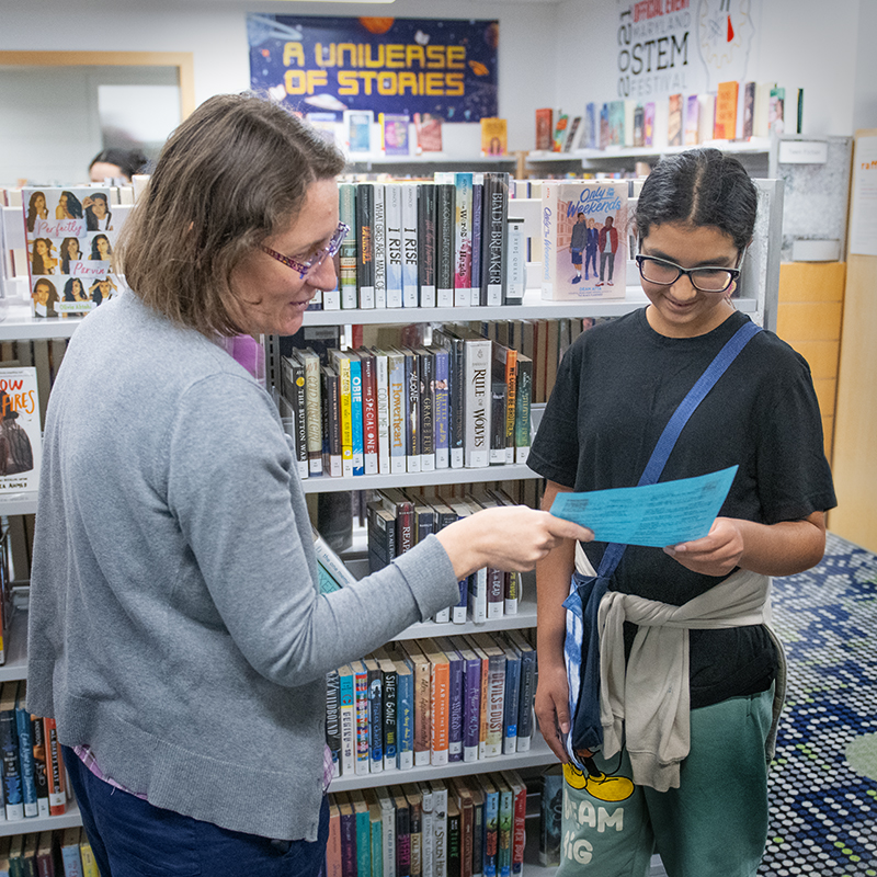Librarian helping a customer pick out books.