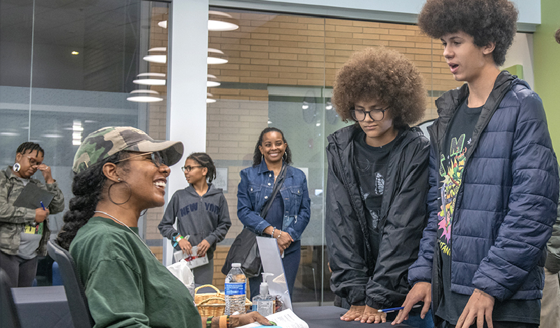Two teenage boys talking to an author at a book signing.
