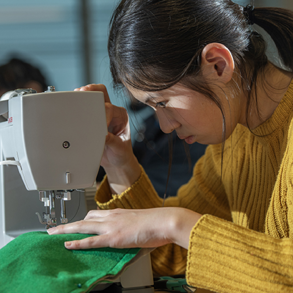 An Adult sewing with one of the free sewing machines available to take home