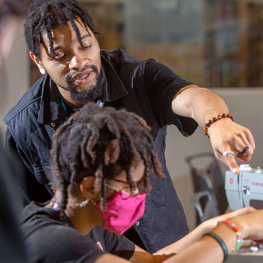 Instructor pointing to a sewing machine.